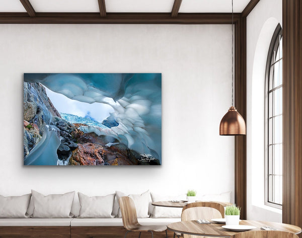 Ice cave photography canvas hangs on a wall in a living room. It is a large piece of art and is the feature piece in the room. The brown in the photograph matches the brown accents in the room. Artwork by Shel Neufeld. 