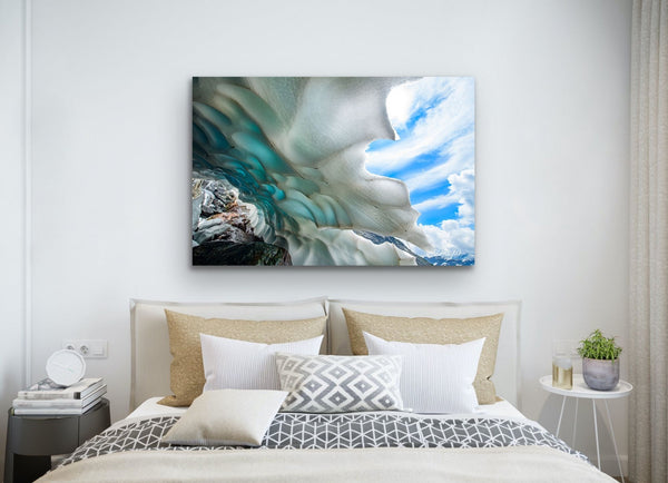 Mountain Ice Cave photography canvas hangs in a bedroom above a bed. Artwork by Shel Neufeld. 