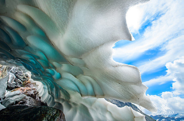 Blue and white ice cave and blue skies overhead. Mountain ice cave captured by Shel Neufeld, Canadian landscape and nature photographer. 