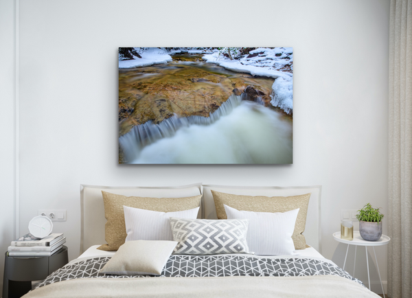 A rock and waterfall form a heart shape in nature. Captured by Shel Neufeld and available as a fine art photography print in a variety of sizes and mediums. The artwork hangs in a bedroom. 