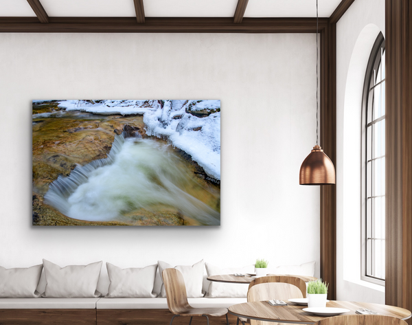 A rock and waterfall form a heart shape in nature. Captured by Shel Neufeld and available as a fine art photography print in a variety of sizes and mediums. The artwork hangs in a living room. 