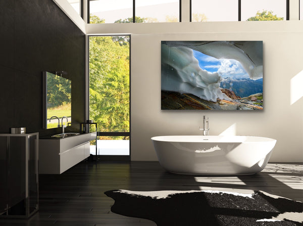 A mountainous ice cave is captured by camera and made into a canvas. The photography canvas hangs in a bathroom above a large soaker tub. Artwork by Shel Neufeld. 