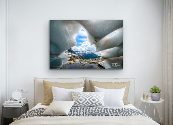 Mountain ice cave photography print hangs above a bed. Photography by Shel Neufeld, Canadian landscape and nature photographer. 