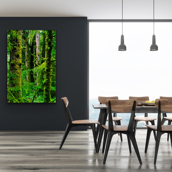 A large nature photograph hangs on the wall of a dining room. The wall art contains a Sitka Spruce forest captured by Shel Neufeld. 