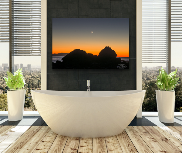 Sombrio Beach orange sunset with moon canvas hangs in a bathroom above a big white soaker tub. Photography by Shel Neufeld, Canadian landscape and nature photographer. 