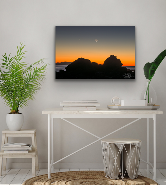Sombrio Beach orange sunset with moon overhead gallery wrapped canvas by Shel Neufeld hangs in a living room.