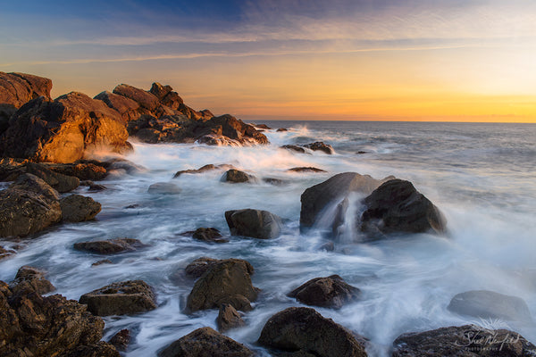 Ucluelet Waves Canvas Wall Art by Shel Neufeld. Coastal Landscape Photography Fine Art Print Canvas Wall Art. This photograph features a beautiful rocky shoreline with soft waves flowing in between rocks. In the distance, the sky is filled with light cloud structure and a warm sunset. The orange and yellow tones fill the blue sky. Photograph by artist Shel Neufeld from Roberts Creek, BC, Canada. 