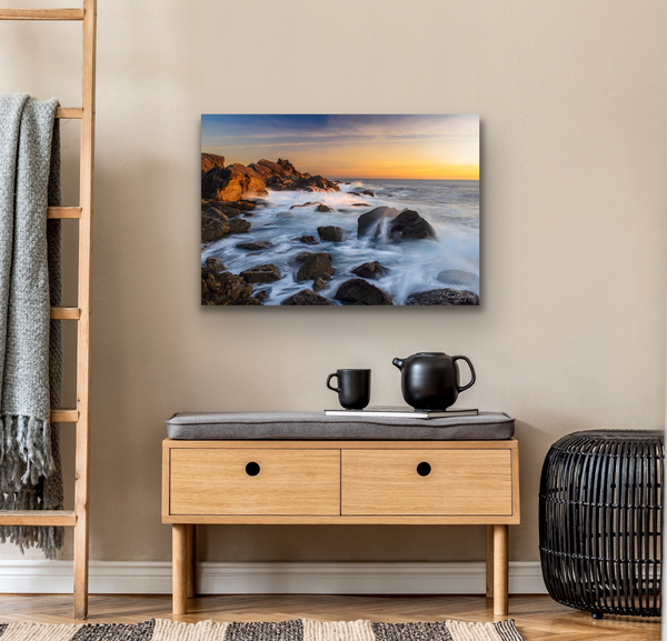 Ucluelet Waves sunset coastal landscape hangs above a tea set in a living room scene. This image is meant to help visualize what the canvas may look like in a room scene. Artwork by Shel Neufeld from Roberts Creek, BC, Canada. 