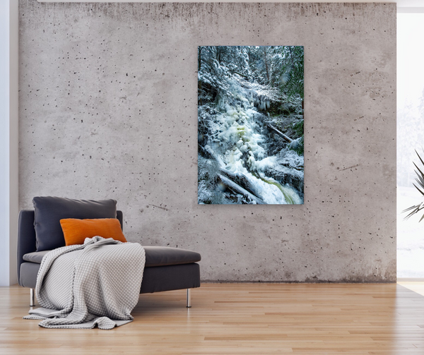 A vertical photography wall art hangs in a living room. The large wall art is a nature scene with icy waterfalls cascading down. Captured by Shel Neufeld. 