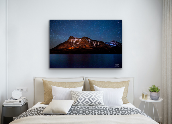 Waterton Peak Astrophotography Canvas hangs above a bed in a white-based bedroom. Artwork by Shel Neufeld, Canadian landscape and nature photographer. 