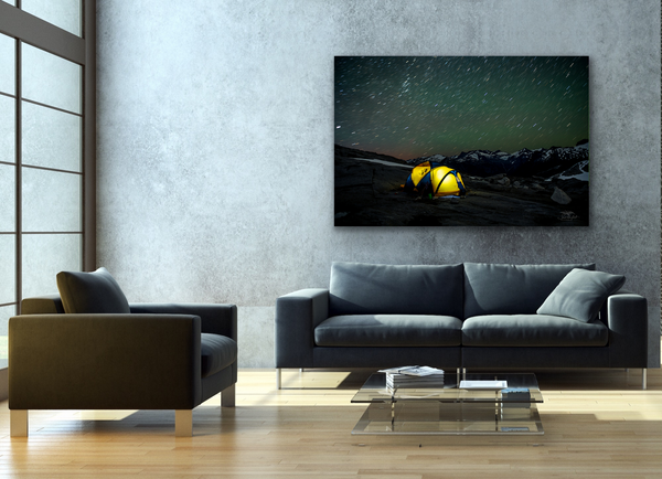 A canvas with a starry night sky and a yellow north face tent are hung on a living room wall. The photography canvas is by Shel Neufeld and is available to shop worldwide. 