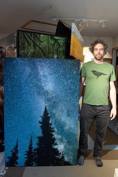 Artist Shel Neufeld stands beside a custom canvas print of his artwork. This large vertical artwork measure 40x60 inches.